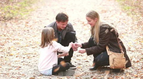 Young family sitting on pathway in park and playing games Stock Footage 59554333