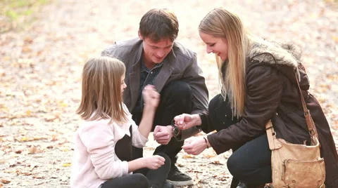 Young family sitting on pathway in park and playing games Stock Footage 59554352