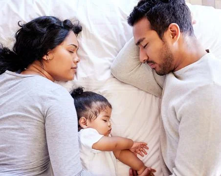 Young family sleeping together from above. Two parents sleeping with their baby Stock Photos