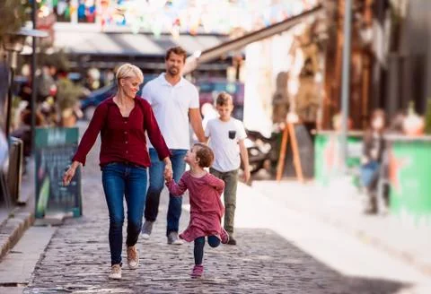 Young family with two small children walking outdoors in town on holiday. Stock Photos
