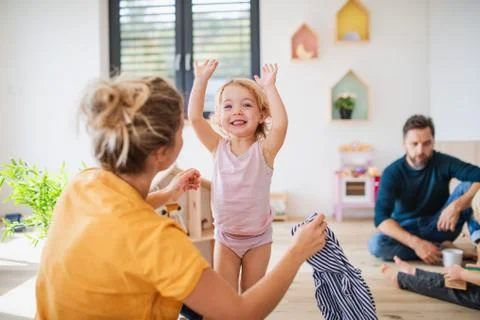 Young family with two small children indoors in bedroom having fun. Stock Photos