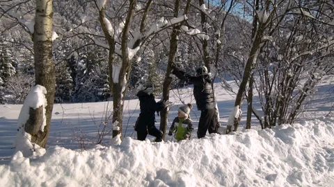 A young family walks through the snow-covered mountain forest. They stand under Stock Footage 100591653