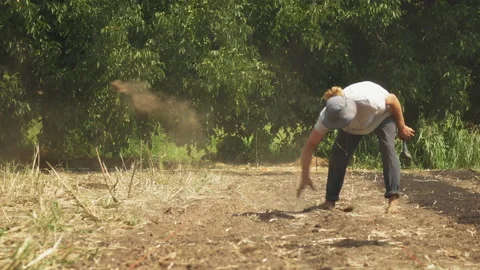 Young farm boy with hat pulling by hand weeds out of his vegetable garden Stock Footage 169704887