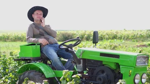 A young farmer driving a mini tractor outdoors in an orchard, he is using a 스톡 동영상 247369438