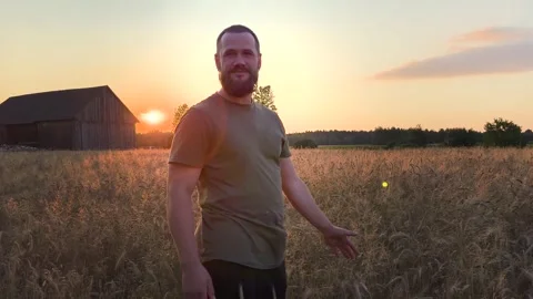 Young farmer standing in a wheat field at golden hour sunset. Stock Footage 342760039