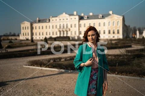 Young fashion lover woman waling in a park wearing vivid green jacket and a Stock Photos