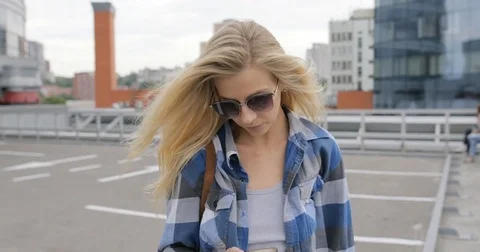 Young fashionable woman calling by smartphone walking in city parking Stock Footage