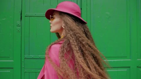 Young fashionable woman with long beautiful curly hair turns around. Model Stock Footage