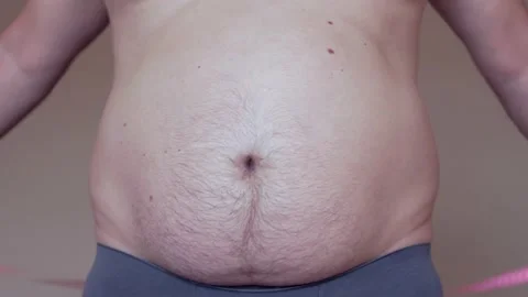 Young fat caucasian guy measures the waist Stock Footage 130797402