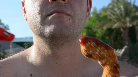 Young fat man drinking beer and eatsfast food near the sea Video stock 97097712