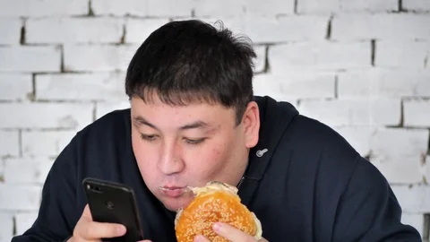 A young fat person eats a Burger Stock Footage 125827788
