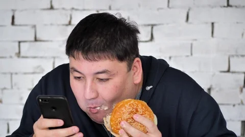 A young fat person eats a Burger Stock Footage 125827795