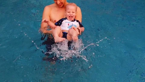 A young father and his two-year-old son are in the pool with blue water Stock Footage 106286953