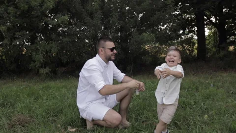 Young father blows bubbles for his happy child in the park Video stock 140883234