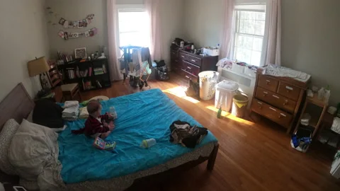 Young father folds laundry while baby plays on bed timelapse Stock Footage 148163011