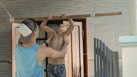 Young father helping child work out pull ups on horizontal bar. Stock Footage 77741823