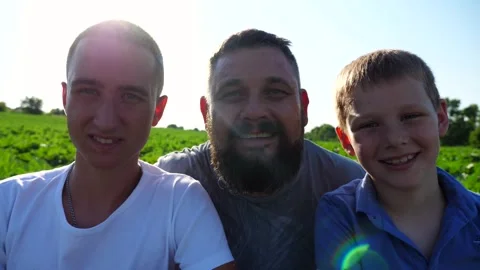 Young father with his two sons looks into camera against background of field Stock Footage 252728357