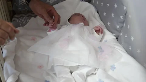 Young father holds tiny hand of newborn sleeping daughter Stock Footage 171327542