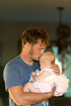Young Father Lovingly Hugging and Kissing Baby Daughter Stock Photos