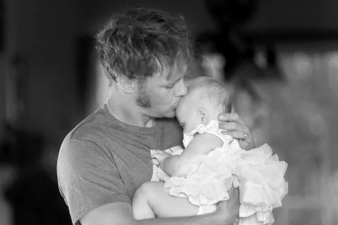 Young Father Lovingly Hugging and Kissing Baby Daughter Stock Photos