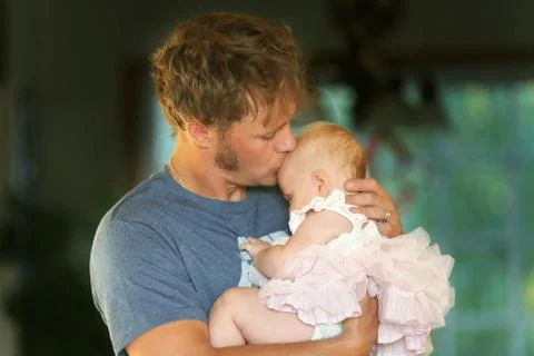 Young Father Lovingly Hugging and Kissing Baby Daughter Stock Photos