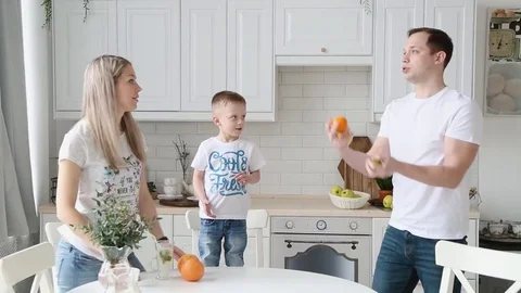 A young father shows the son in the kitchen how to juggle oranges Stock Footage 76092406