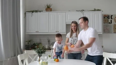 A young father shows the son in the kitchen how to juggle oranges Stock Footage 84497595