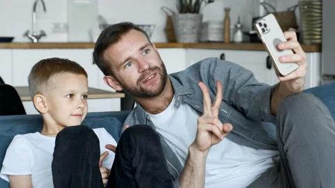 Young father spend time with son having fun using smartphone at home Stock Footage 156809165
