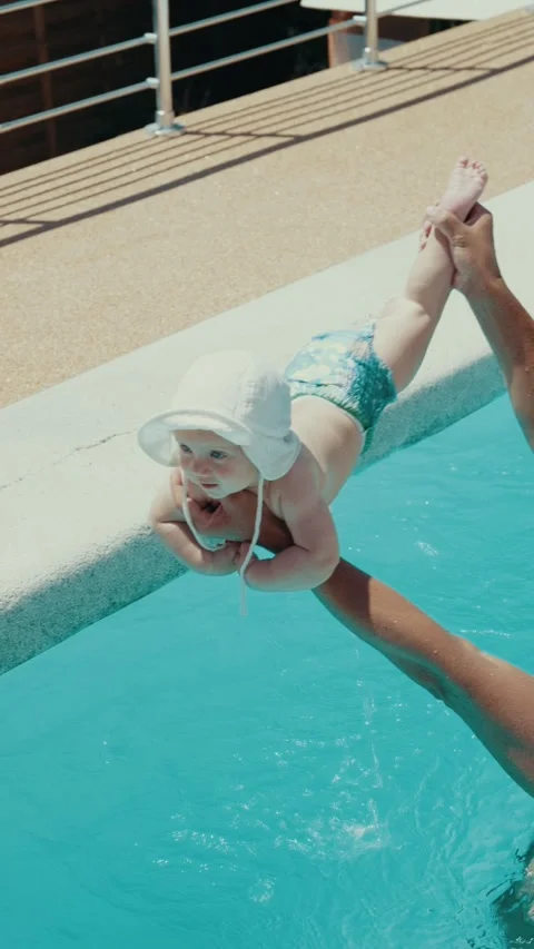 Young father teaching his cute baby to swim for the first time in a bright blue Stock Footage 339278055