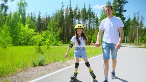 Young father walking towards camera on street and supporting little daughter whi Stock Footage 280209917
