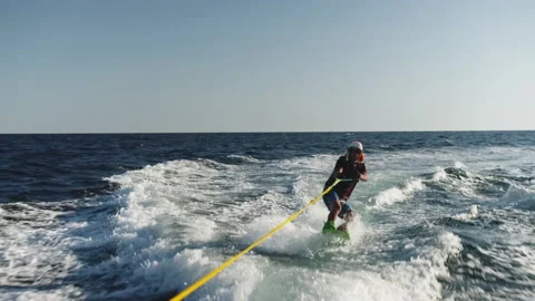 Young fellow in funny cap is riding fast over the waves across the sea. person Stock Footage 201345299