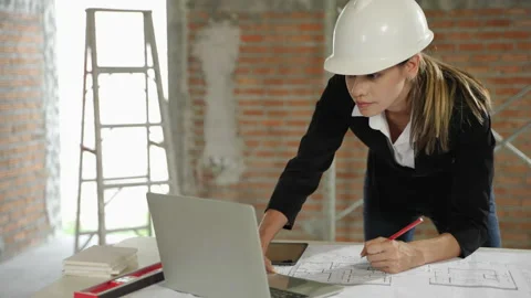 Young female architect checking blueprints inside a building Stock Footage 226814150