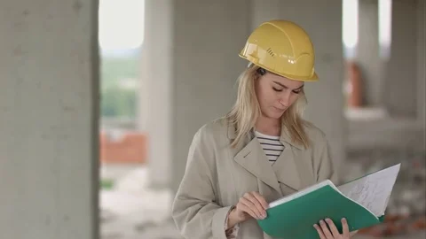 Young female architect construction engineer at a construction site eximaining Stock Footage 82801155