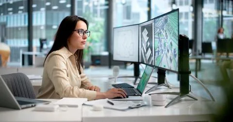 Young Female Architect Using Laptop To Review Detailed 3D Building Design. Stock Photos