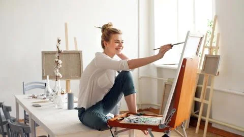 Young female artist draws a picture on canvas using a brush and oil Stock Photos