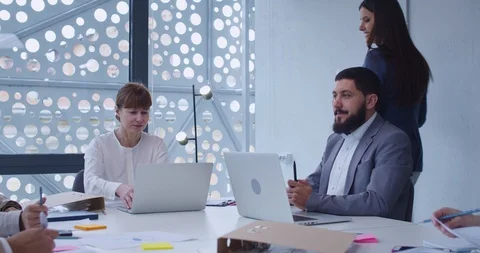Young female assistant handing documents to men and women at laptop computers Stock Footage 129517609