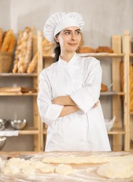 Young female baker at table with dough Photos