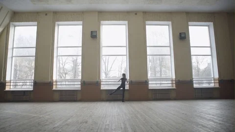 Young female ballet dancer exercising at the barre by the window in studio Vídeo Stock 72607646