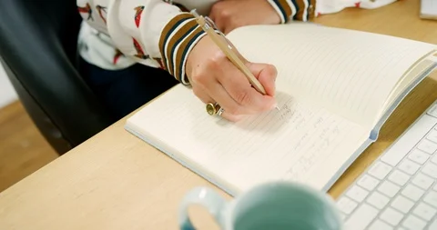 Young Female Blogger Making Notes At Desk In Home Office Stock Footage 100043864