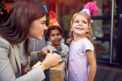Young female brunette opening  birthday presents to a little girl looking awa Stock Photos