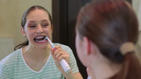 Young female brushing teeth with braces in the bathroom. Health care, dental Stock Footage 173792124