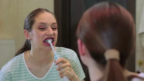 Young female brushing teeth with braces in the bathroom. Health care, dental Stock Footage 186787987