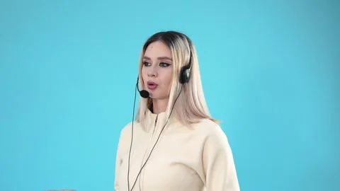 Young Female Call Center Operator Talking on Headset Against Blue Background Vídeo Stock 346111144
