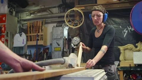 Young female carpenter cutting wood on table saw in a crative workshop leaving Stock Footage