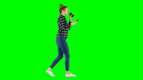 Young Female Checks Smartphone While Walking and Drinking Coffee on Green Screen Stock Footage 124508970