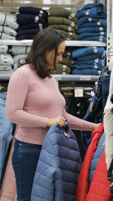 Young female choosing winter jacket in store Stock Footage 322219686