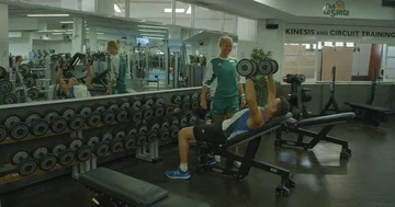 A young female coach instructs a middle aged man weight training in a gym Vídeo Stock 85574891