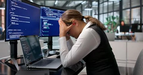 Young Female Coder Facing Migraine Pain While Working Late At Her Desk. Stock Photos