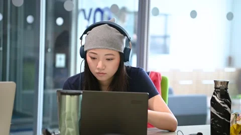Young female computer programmer with headpohones working at laptop Stock Footage 220346089