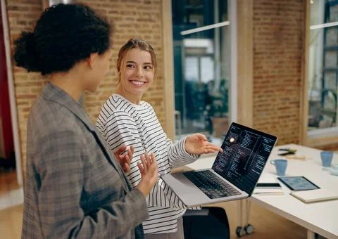Young female computer programmers is coding at laptop while standing in 스톡 사진